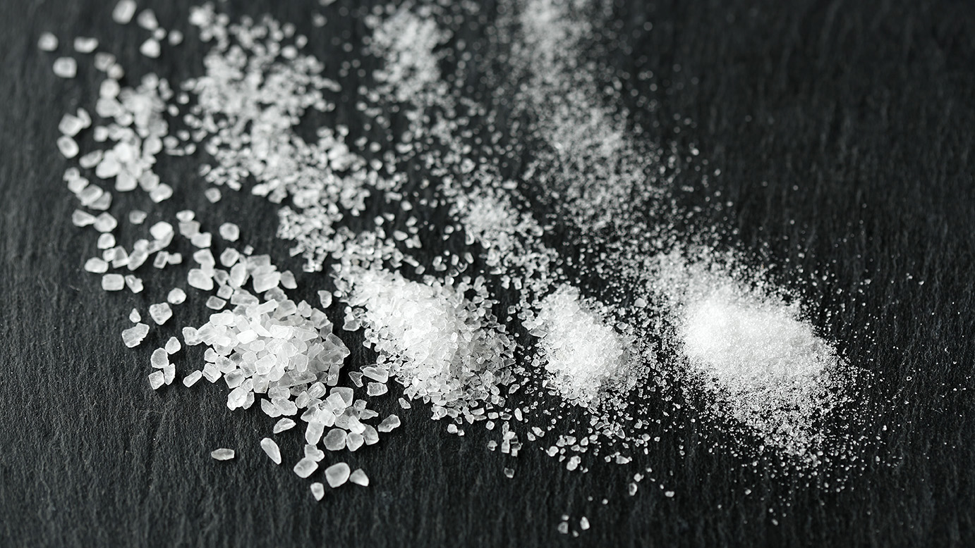 Various salt grains scattered on a slate plate